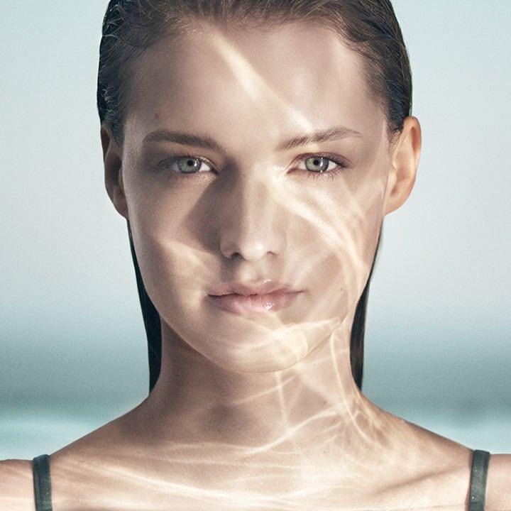A female model immersed in water, representing the soothing and hydrating effects of Crème de La Mer Moisturizing Cream, White, known for its Miracle Broth formula.