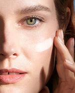 A female model applying Crème de La Mer, Moisturizing Cream to her face. The luxurious white cream visibly enhances skin texture and hydration, part of an effective anti-aging skincare routine.