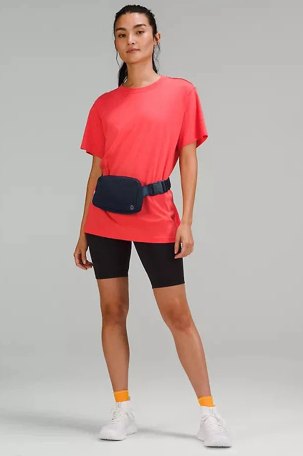 A_women_modeling_the_Lululemon_Everywhere_Belt_Bag_1L_in_Black_worn_over_the_waist_highlighting_its_adjustable_strap_and_versatile_wear_for_everyday_use.