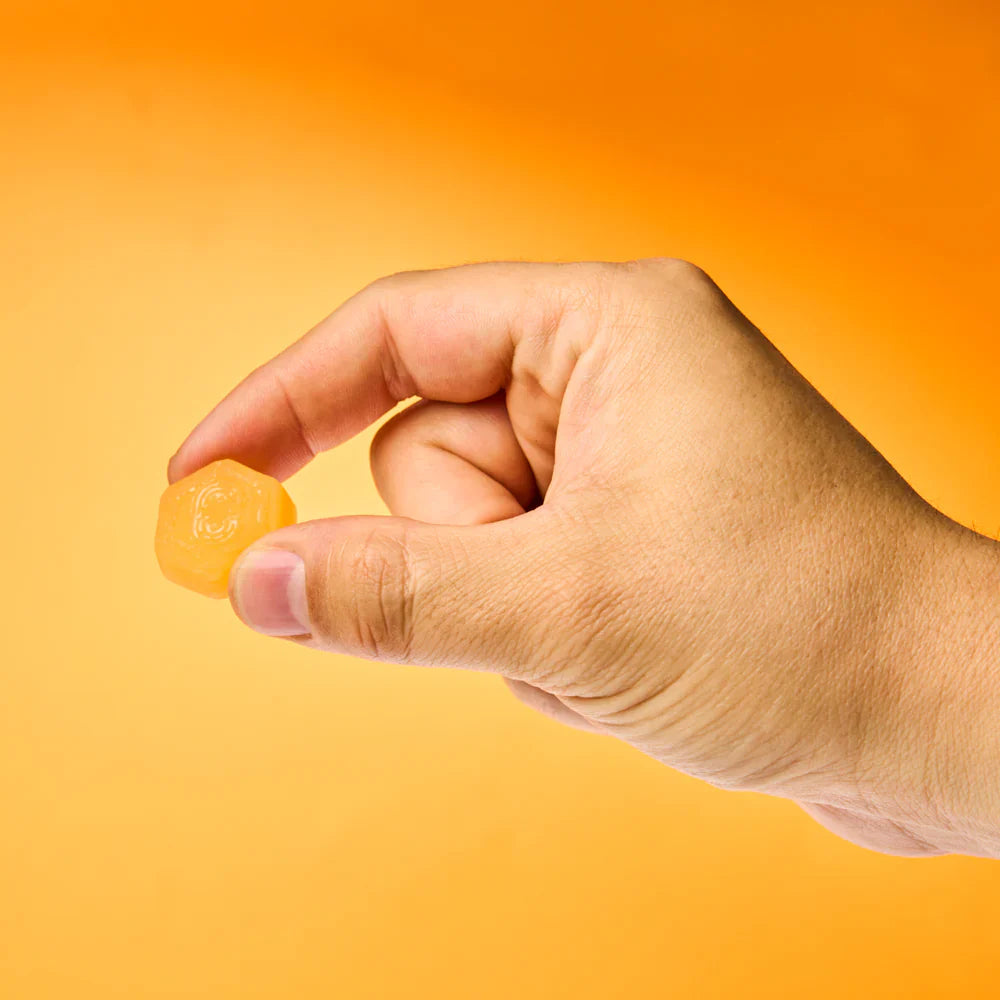 A close-up of a man’s hand holding a single Creatine Monohydrate Gummy, highlighting the convenience and ease of taking this tasty, muscle-supporting supplement as part of a daily workout routine.