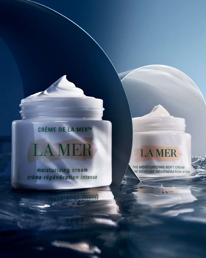 Two front views of Crème de La Mer, Moisturizing Cream, White, showcasing the elegant packaging with the cream popping up. This high-end cream provides rich moisture and helps reduce fine lines.